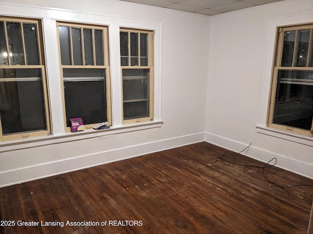 unfurnished room featuring dark wood-type flooring and baseboards