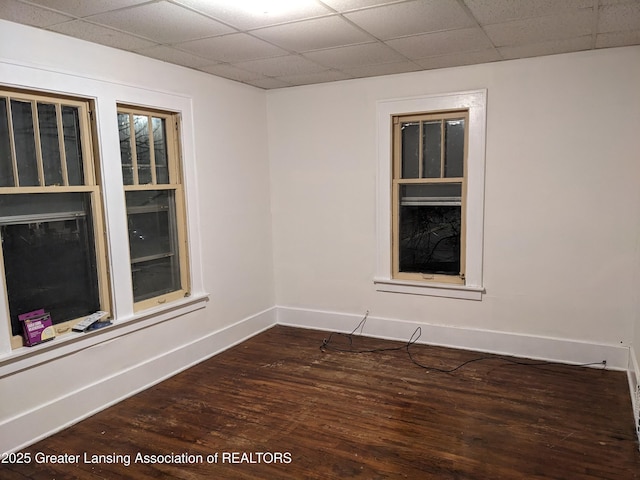 spare room with dark wood finished floors, baseboards, and a paneled ceiling