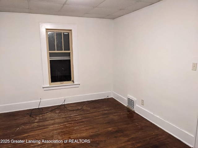 unfurnished room with visible vents, baseboards, dark wood-type flooring, and a paneled ceiling
