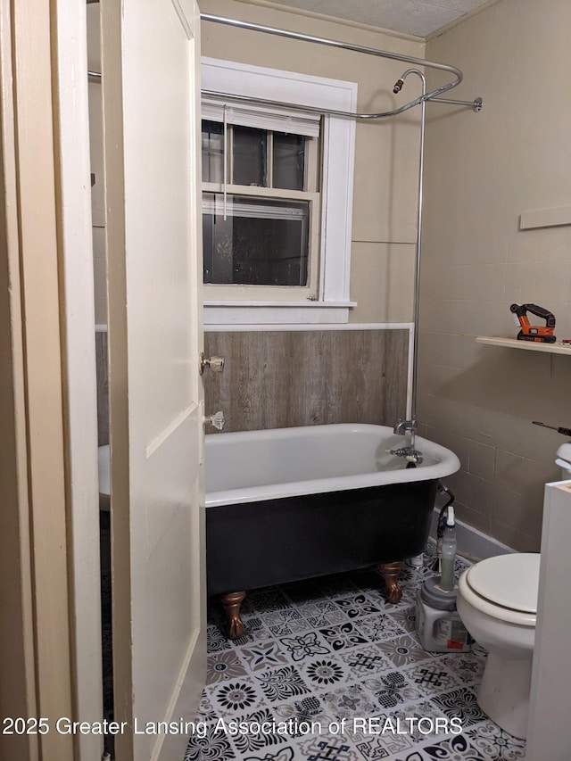 full bath featuring toilet, tile patterned floors, and a washtub