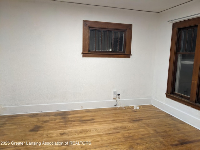 spare room featuring baseboards and wood finished floors