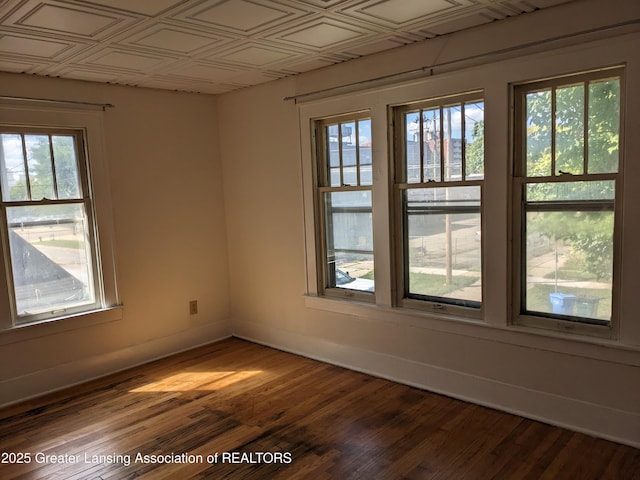 unfurnished room with baseboards and dark wood-style floors