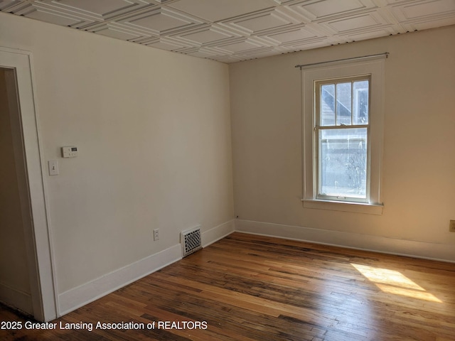 spare room with an ornate ceiling, hardwood / wood-style flooring, baseboards, and visible vents