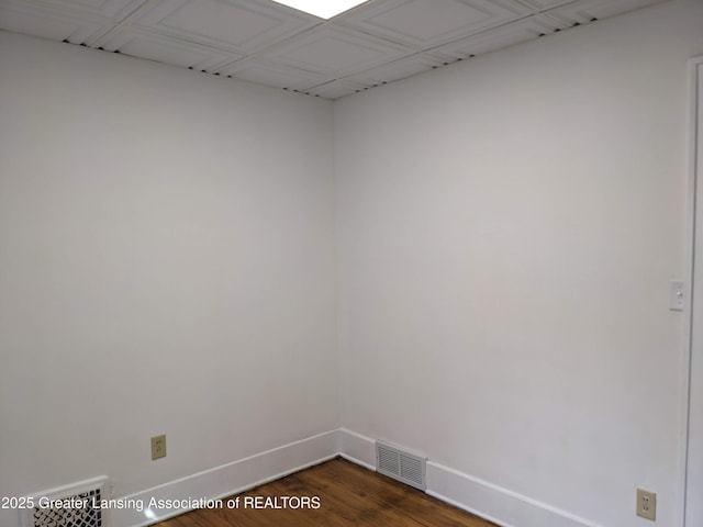 spare room featuring baseboards, visible vents, and dark wood finished floors
