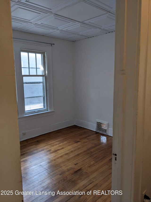 spare room with visible vents, wood finished floors, and baseboards