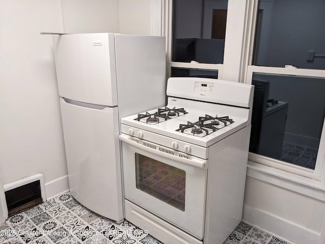 kitchen with light countertops, light tile patterned floors, baseboards, and white appliances