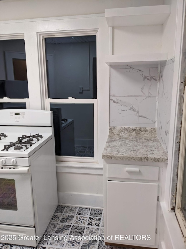 interior space featuring white cabinetry, white range with gas cooktop, and decorative backsplash