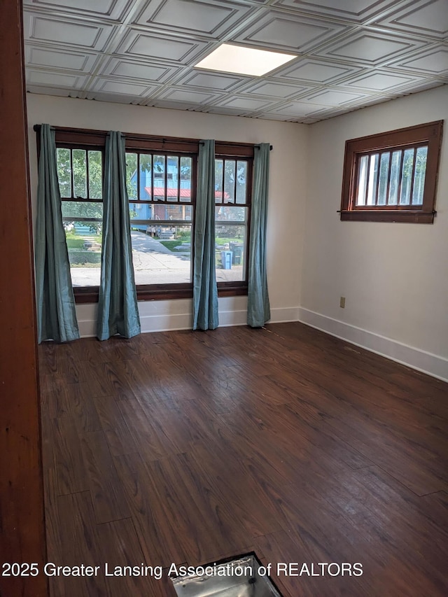 unfurnished room featuring baseboards, an ornate ceiling, and dark wood-style floors