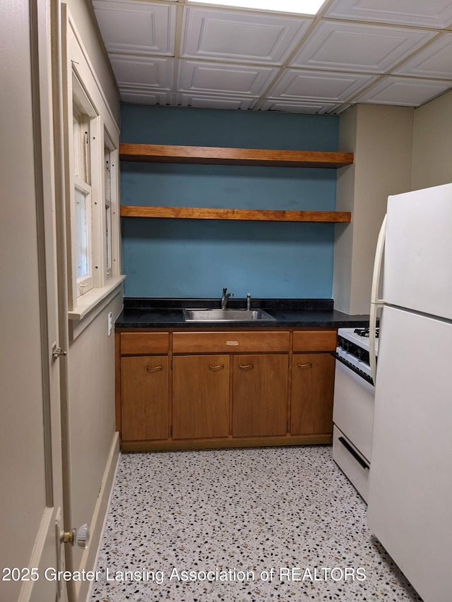 kitchen featuring brown cabinets, a sink, open shelves, dark countertops, and white appliances