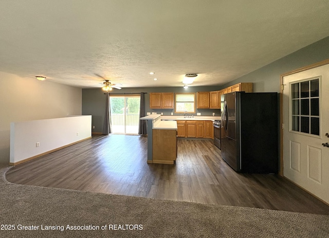 5205 N Bailey Rd, Coral, MI 49322 - kitchen featuring freestanding refrigerator, light countertops, dark wood-style flooring, open floor plan, and gas range oven