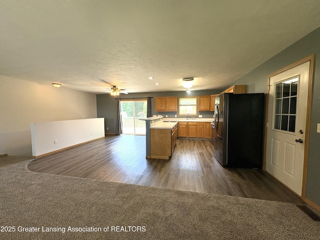 5205 N Bailey Rd, Coral, MI 49322 - kitchen with freestanding refrigerator, light countertops, brown cabinetry, dark wood-style floors, and dark carpet