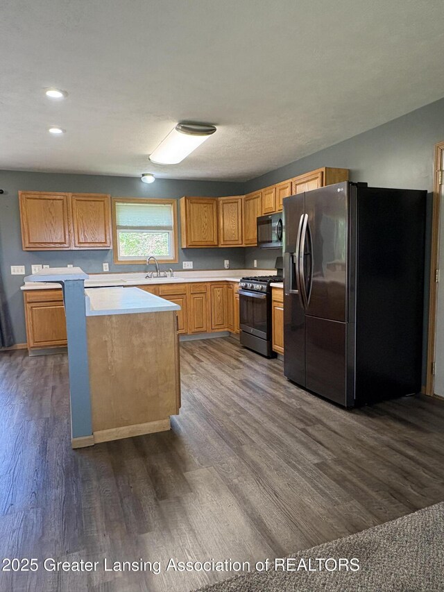 5205 N Bailey Rd, Coral, MI 49322 - kitchen with fridge with ice dispenser, gas range oven, black microwave, light countertops, and dark wood finished floors