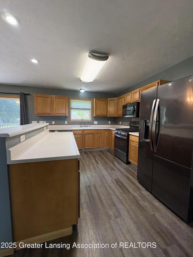 5205 N Bailey Rd, Coral, MI 49322 - kitchen with fridge with ice dispenser, gas range, black microwave, dark wood-style flooring, and light countertops