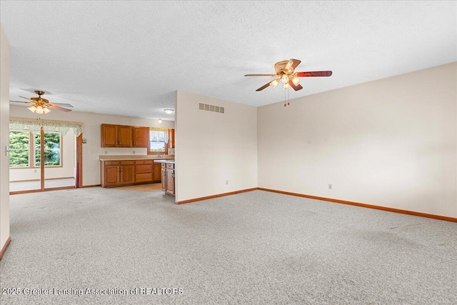 unfurnished living room featuring a ceiling fan, baseboards, visible vents, and light colored carpet