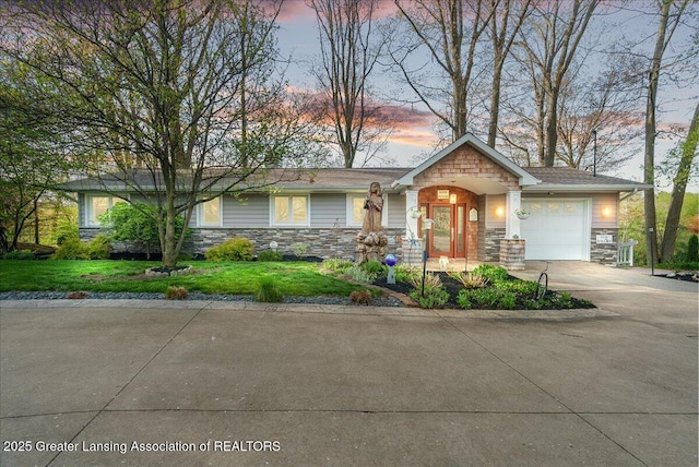 view of front of property featuring concrete driveway, an attached garage, a front lawn, and stone siding