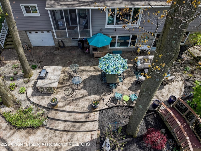 view of yard with an attached garage, a sunroom, and a patio