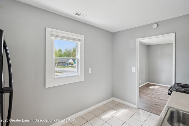 1406 N Martin Luther King Jr Blvd, Lansing, MI 48915 - kitchen with light tile patterned floors, visible vents, baseboards, and black appliances