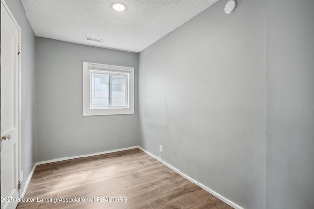 1406 N Martin Luther King Jr Blvd, Lansing, MI 48915 - spare room featuring a textured ceiling, baseboards, visible vents, and wood finished floors