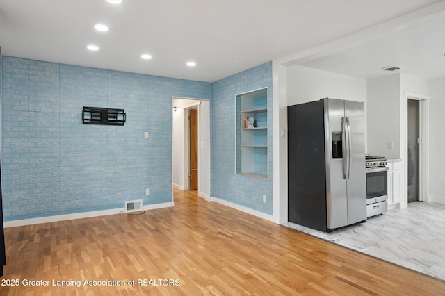 900 Holten St, Lansing, MI 48915 - kitchen featuring appliances with stainless steel finishes, light wood finished floors, baseboards, recessed lighting, and brick wall