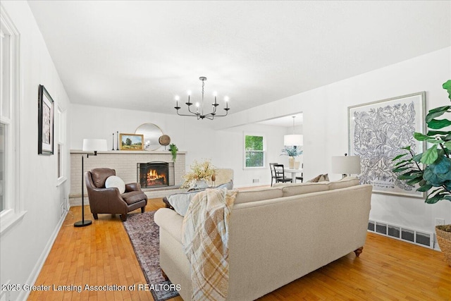 living area with baseboards, a chandelier, visible vents, and light wood-style flooring