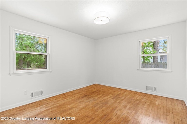 unfurnished room with visible vents, light wood-style flooring, and baseboards