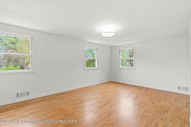 spare room featuring light wood-type flooring, baseboards, and visible vents