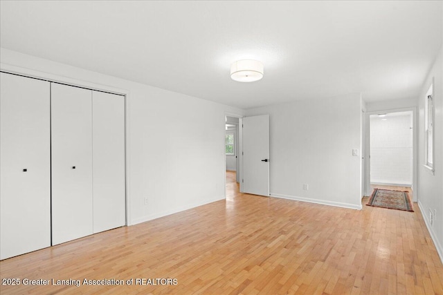 unfurnished bedroom with a closet, light wood-style floors, and baseboards