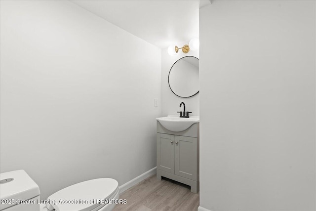 bathroom featuring toilet, baseboards, vanity, and wood finished floors