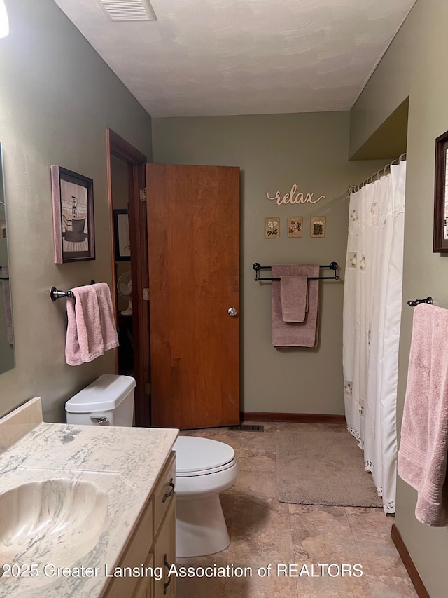 bathroom featuring toilet, vanity, baseboards, and a shower with shower curtain