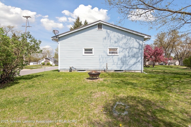 view of home's exterior featuring a fire pit and a lawn