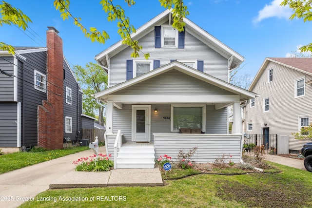 american foursquare style home with a porch and fence