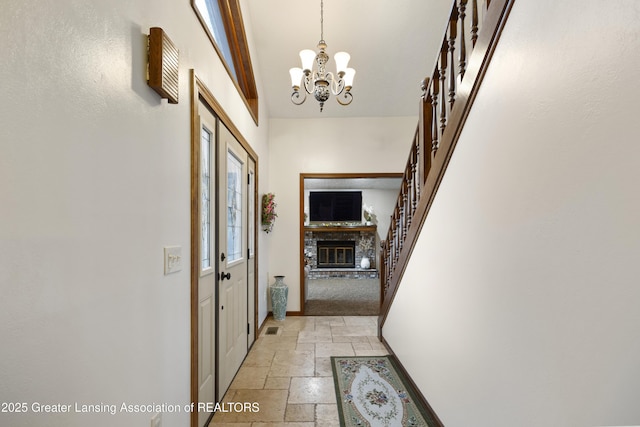 corridor with stone tile flooring, a chandelier, baseboards, and vaulted ceiling