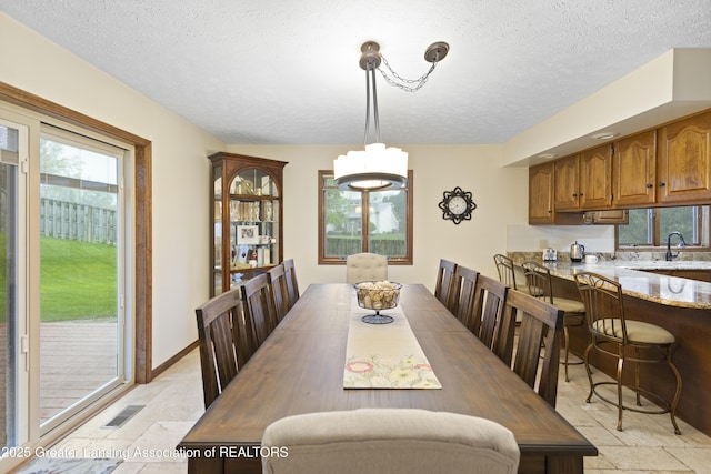 dining area with stone tile floors, a chandelier, and a textured ceiling