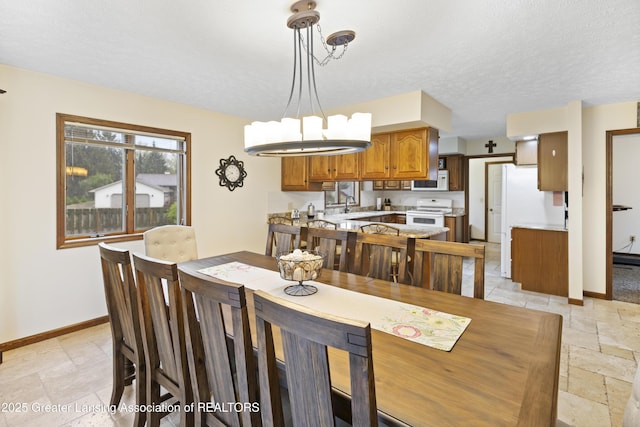 dining room featuring stone tile floors, baseboards, and a textured ceiling