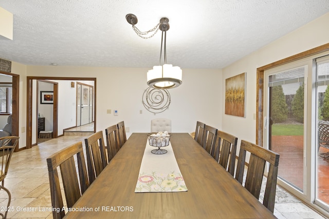 dining room featuring a textured ceiling, stone tile flooring, and a chandelier