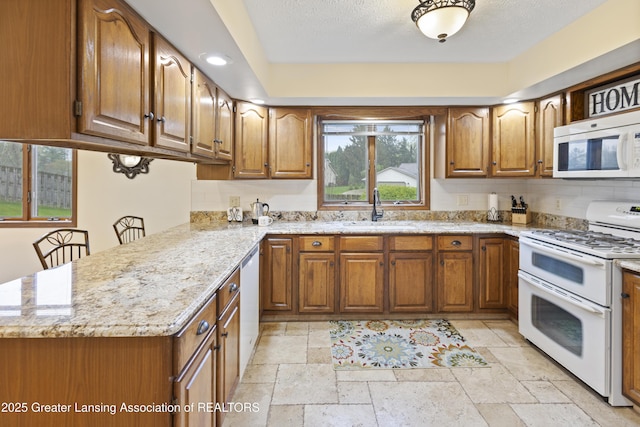 kitchen featuring white appliances, a sink, stone tile flooring, and brown cabinets