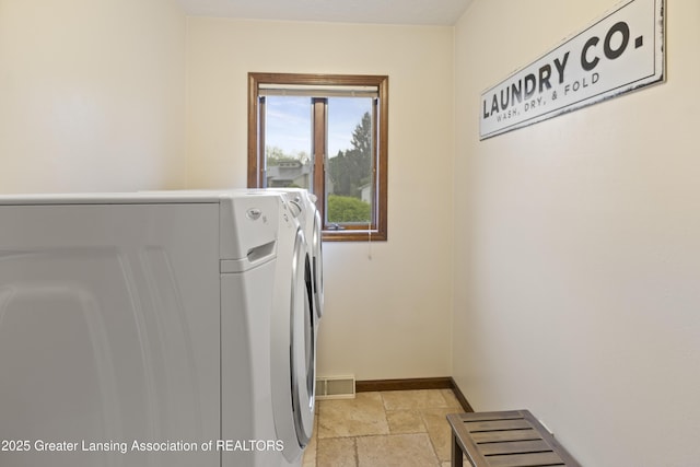 washroom featuring independent washer and dryer, stone tile floors, and baseboards