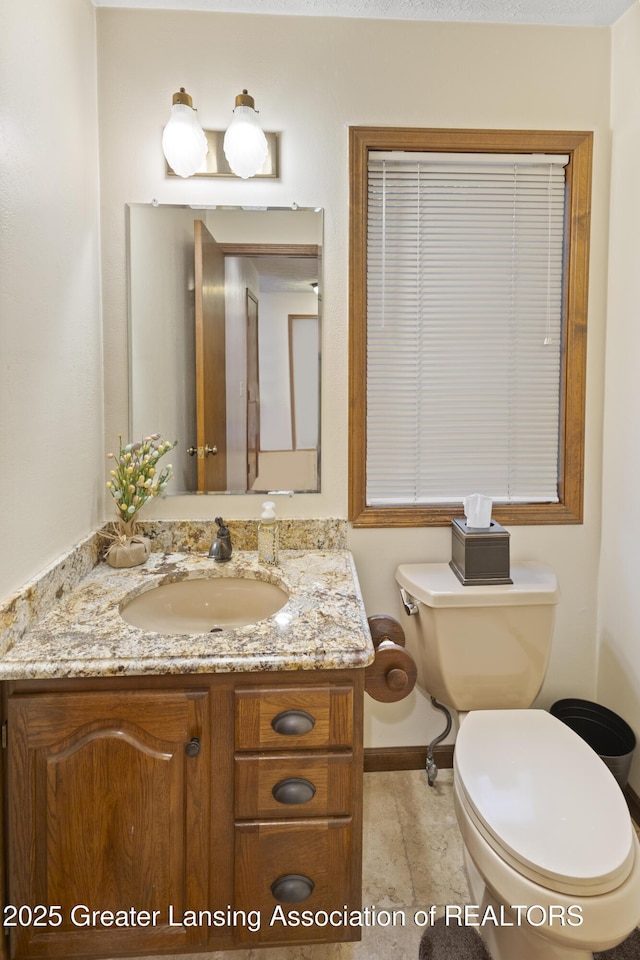 bathroom with toilet, vanity, and baseboards
