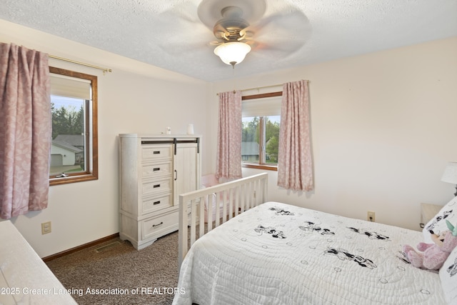 bedroom featuring multiple windows, baseboards, carpet, a ceiling fan, and a textured ceiling