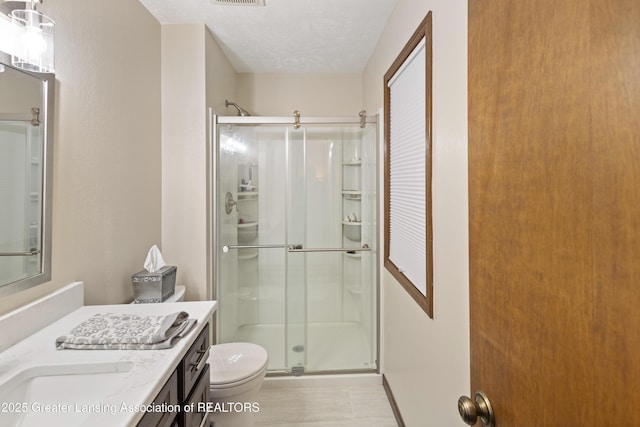 full bathroom with a stall shower, toilet, vanity, and a textured ceiling