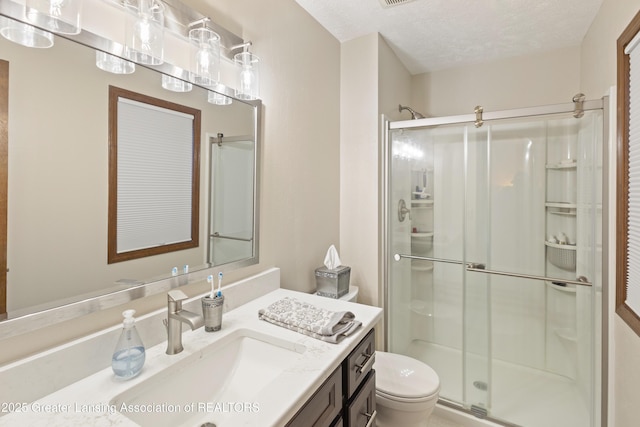 full bathroom featuring a stall shower, toilet, vanity, and a textured ceiling