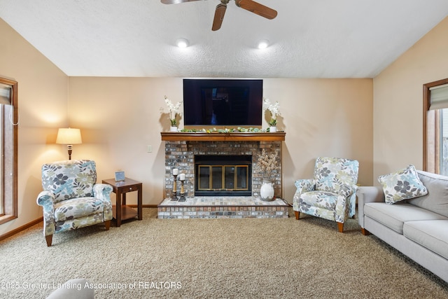 living room with carpet flooring, a ceiling fan, a glass covered fireplace, and a textured ceiling