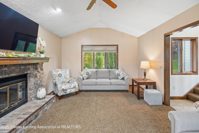 living room featuring carpet, a ceiling fan, vaulted ceiling, a fireplace, and baseboards