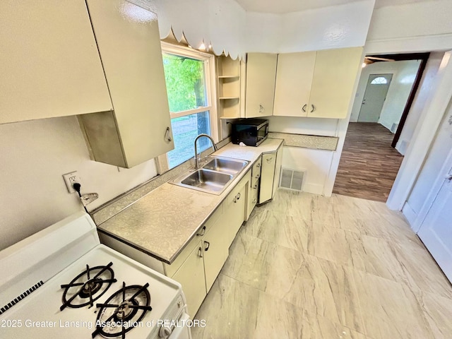 kitchen featuring a sink, open shelves, white range with gas cooktop, visible vents, and light countertops