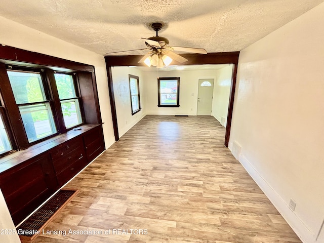 corridor featuring baseboards, a textured ceiling, and wood finished floors