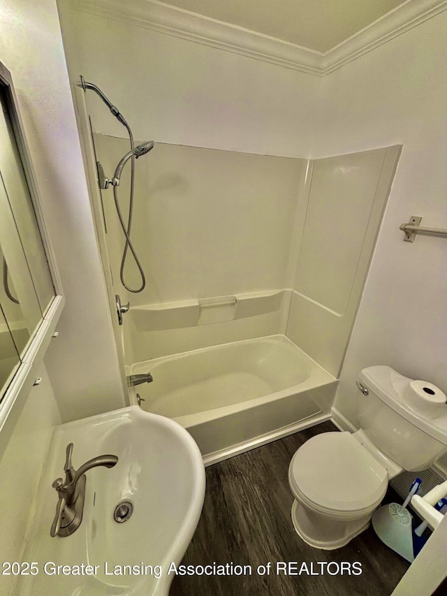 bathroom with a sink, shower / bathing tub combination, toilet, wood finished floors, and crown molding