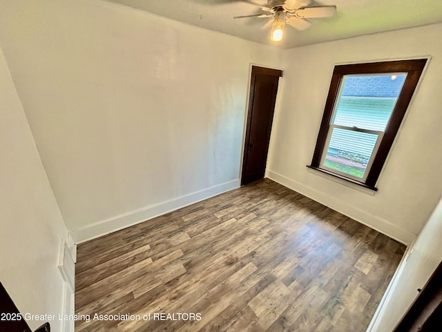 unfurnished room with a ceiling fan, wood finished floors, and baseboards