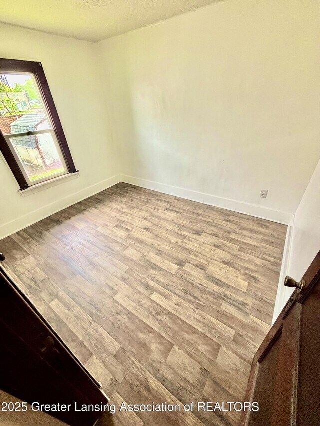 spare room featuring baseboards and wood finished floors