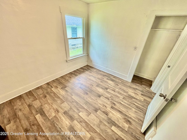 unfurnished bedroom featuring baseboards, a closet, and wood finished floors