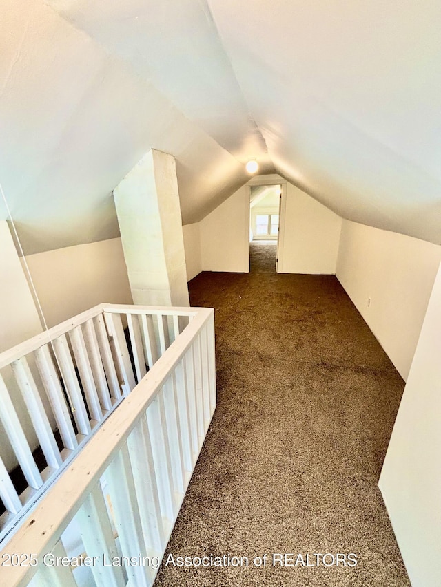 bonus room featuring dark colored carpet and lofted ceiling